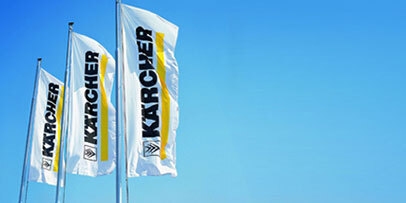 Three Kärcher flags fly with a blue sky in the background