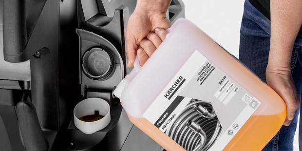A worker uses pressure washer maintenance detergent.