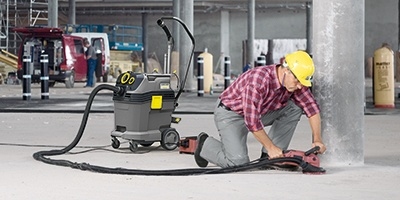 A worker vacuums fine dust and debris using a wet dry vac.