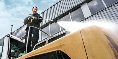 A worker pressure washes heavy duty cleaning equipment.