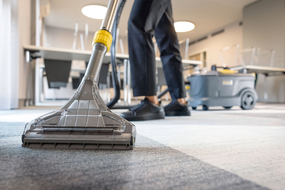 A close-up of a person using a carpet extractor.