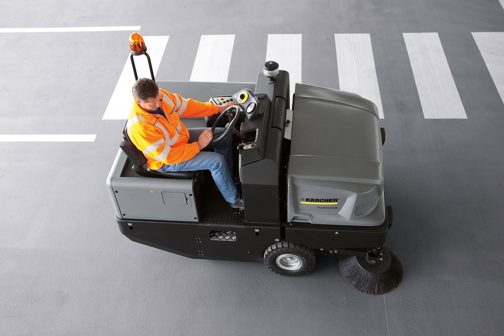 An aerial view of a worker sweeping floors in a parking garage..