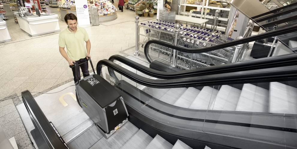 A worker cleans an escalator with Kärcher commercial cleaning equipment.