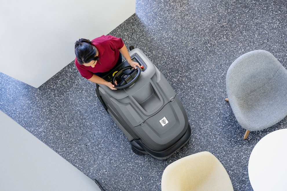 Overhead view of a worker cleaning carpets with a Karcher stand-on vacuum