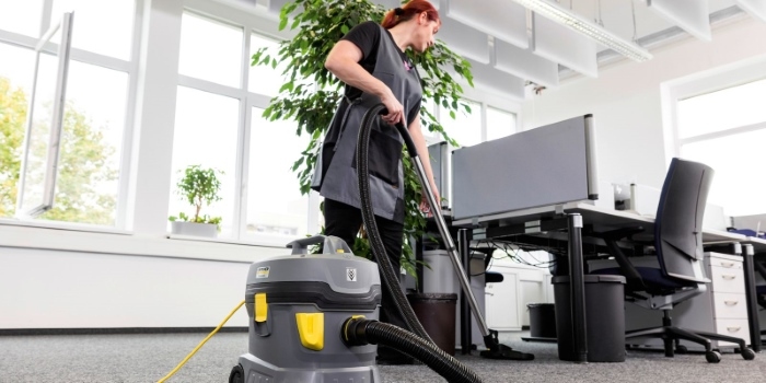 Woman using Karcher vacuum to clean office carpet