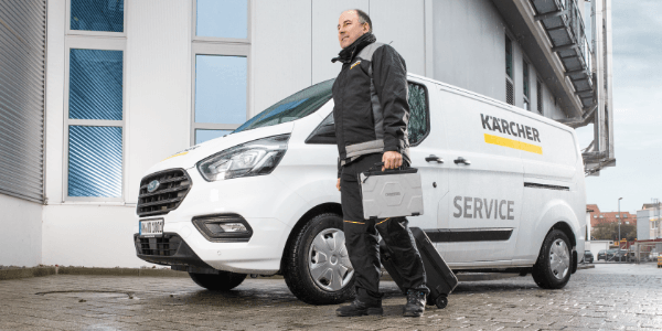 A Kärcher Service rep walks from his van with tools in hand.