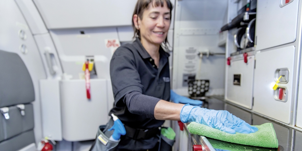 A person cleaning the interior of an airplane with a microfiber cloth