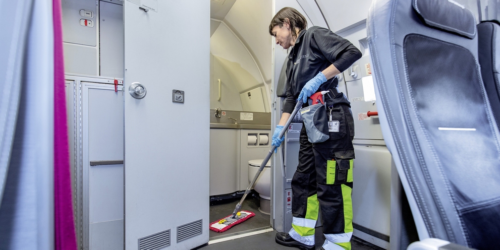A person cleaning the toilet area with a mop