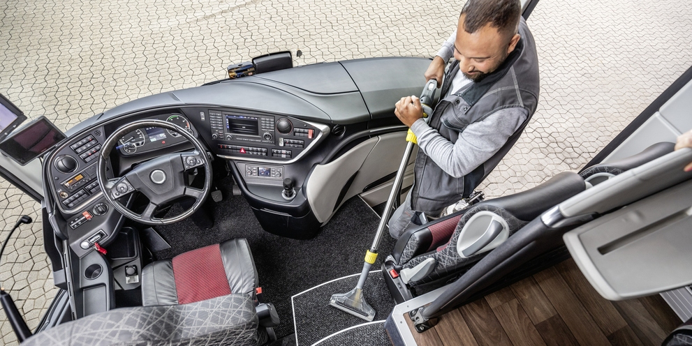 A person cleaning the entrance area of a bus with a mini scrubber dryer