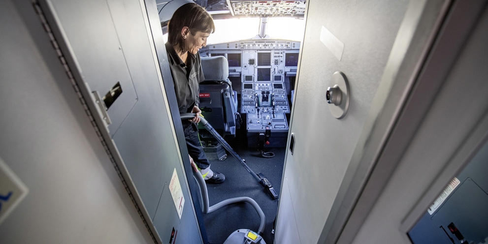A person cleaning the cockpit of an airplane with a Kärcher dry vacuum cleaner