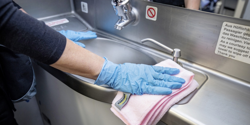 A person cleaning a sink with a microfiber cloth