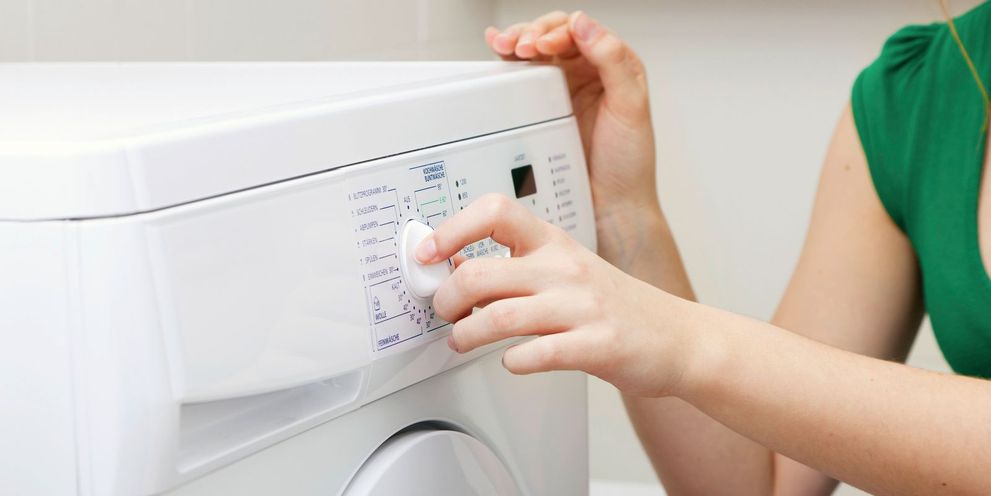 Eco programme for the washing machine A woman setting the washing machine to the eco programme
