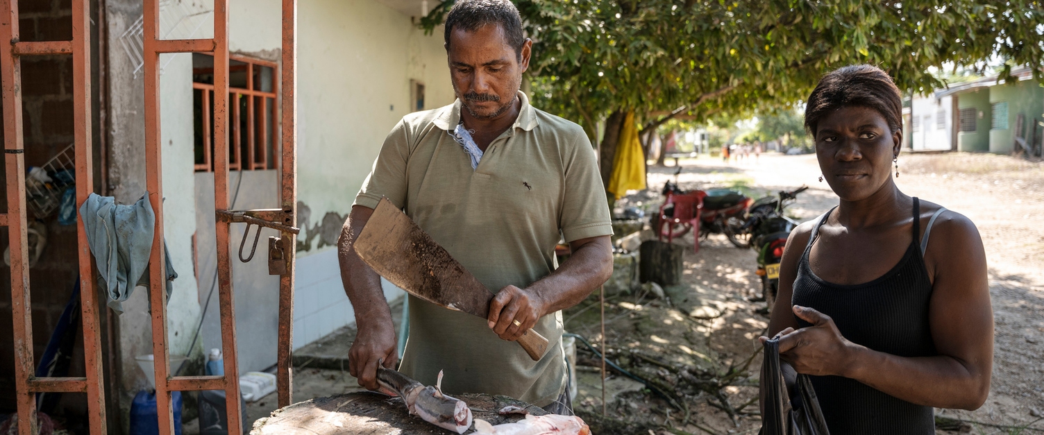 A couple prepares fresh fish. Most of the residents live from fishing. The photo shows a married couple. The man is cutting up a freshly caught fish.