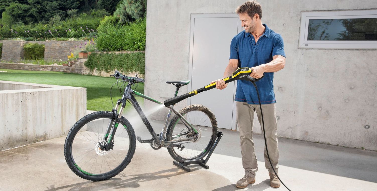 Bicycle cleaning with pressure washer A man cleans his mountain bike with a Kärcher pressure washer