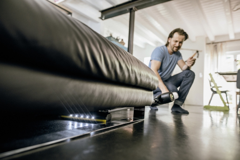 VC 6 Cordless dulkių siurblys Asmuo, siurbiantis po sofa su „Kärcher VC 6“ dulkių siurbliu