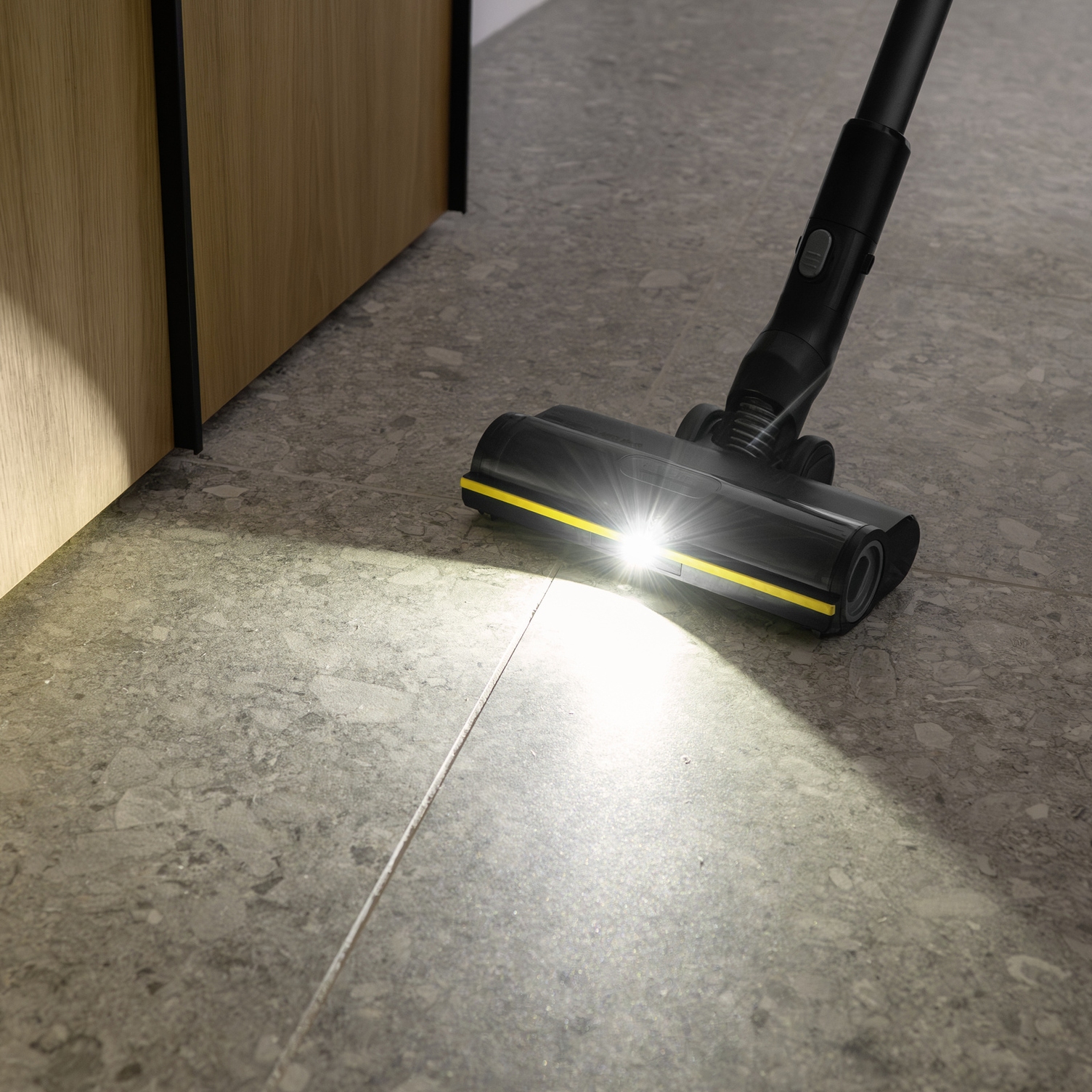 125° wide-angle floor light for cleaning without missed spots Kärcher battery-powered vacuum cleaner using LEDs to illuminate fine dust on a dark tiled floor.