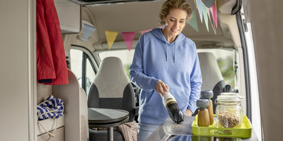 Compact Kärcher handheld vacuum cleaners for maximum mobility Woman cleaning a shelf in a motorhome with a compact Kärcher handheld vacuum cleaner.