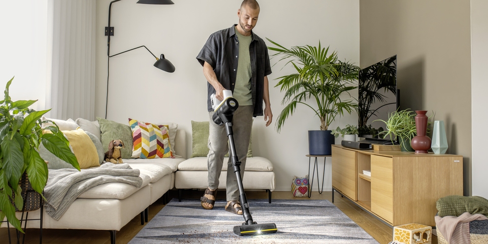 Discover the Kärcher battery-powered vacuum cleaner range Man vacuuming a living-room carpet with a Kärcher battery-powered vacuum cleaner.
